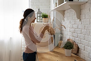 Smiling woman decorating new apartment, making bouquet of dry plants