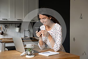 Smiling woman distracted form computer work using cellphone