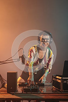 Smiling woman dj mixing sounds at turntables