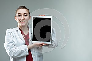 Smiling woman doctor holding up a blank tablet pc