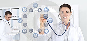 Smiling woman doctor with stethoscope pointing medical symbols icons on medical clinic background