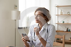 Smiling woman doctor using smartphone at workplace