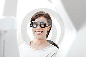 smiling woman doing eyesight measurement wears trial frame isolated on white