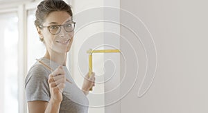 Smiling woman doing a home makeover and measuring with a ruler