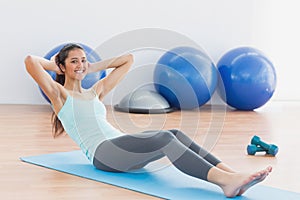 Smiling woman doing sit ups in fitness studio