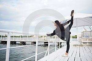 Smiling woman doing yoga exercise outdoors on the beach pier