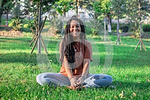 Smiling woman is doing yoga exercise outside in a park. Concept of healthy lifestyle