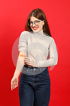 Smiling woman after donating blood at a transfusion center on a red background, vertically