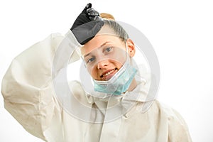 Smiling woman with downcast mask wipes her forehead with hand