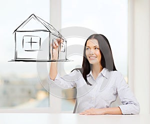 Smiling woman drawing house on virtual screen