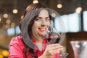 Smiling woman drinking red wine at restaurant