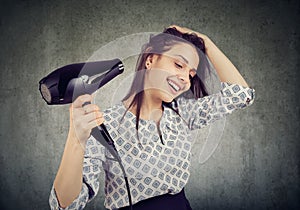 Smiling woman drying her hair with a hairdryer