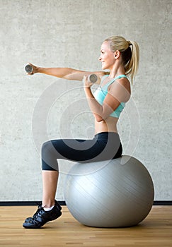 Smiling woman with dumbbells and exercise ball