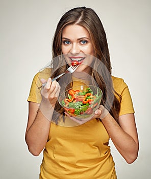 Smiling woman eatin vegatable salad with fork