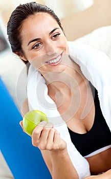 Smiling woman eating an apple after working out