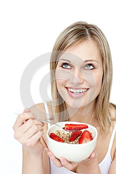 Smiling woman eating cereals with strawberries