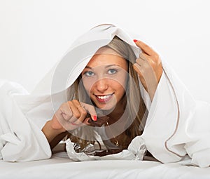 Smiling woman eating chocolate in her bed