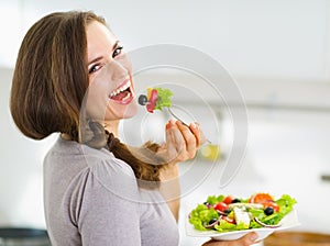 Donna sorridente mangiare fresco insalata la cucina 