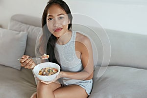 Smiling woman eating healthy breakfast at home in morning