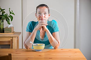 Smiling woman eating kitchari for a breakfast.