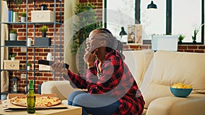 Smiling woman eating pizza and watching tv show