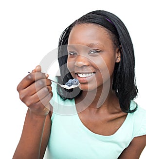 Smiling woman eating a yogurt with blueberries