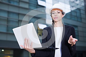 Smiling woman engineer in suit and hat with laotop is pleased with realisation her project