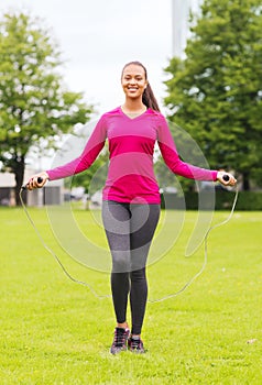 Smiling woman exercising with jump-rope outdoors