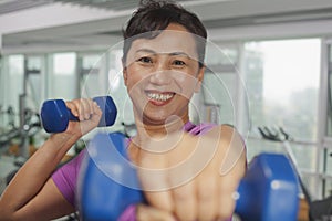 Smiling woman exercising with weights and looking at camera