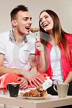 Smiling woman feeding happy man with cake.
