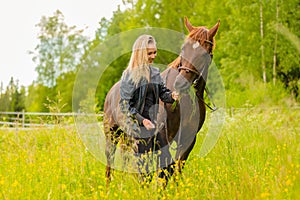 Smiling woman feeding her arabian horse with snacks in the field