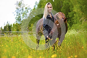 Smiling woman feeding her arabian horse with snacks in the field