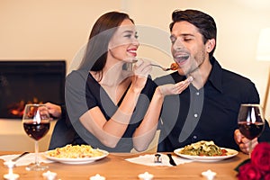 Smiling woman feeding her man with pasta