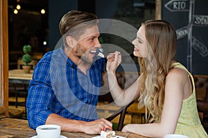 Smiling woman feeding man while sitting at table