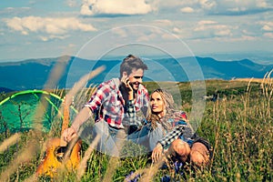 Smiling woman flirt with handsome man at the mountainside having rest at the nature. Travel couple enjoying wanderlast