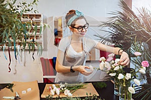 Smiling woman florist making bouquet in flower shop