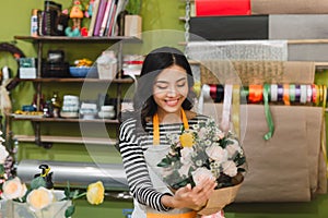 Smiling woman florist, small business flower shop owner, at counter, looking friendly at camera working at a special flower