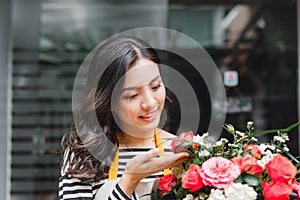 Smiling woman florist, small business flower shop owner, at counter, looking friendly at camera working at a special flower