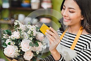 Smiling woman florist, small business flower shop owner, at counter, looking friendly at camera working at a special flower