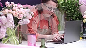 Smiling woman florist small business flower shop owner using laptop to take online orders
