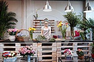 Smiling woman florist standing and working in flower shop