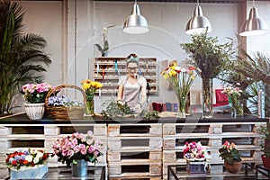Smiling woman florist standing and working in flower shop