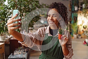 Smiling woman florist taking selfie with her plants for publishing in social media