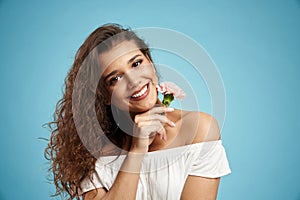 Smiling woman with flower, isolated on blue.