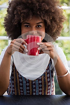 Smiling woman with frizzy hair having coffee in cafe