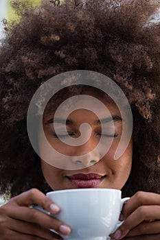 Smiling woman with frizzy hair smelling coffee