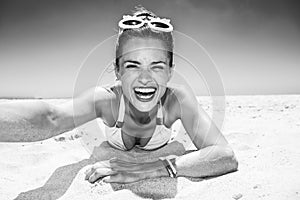 Smiling woman in funky glasses taking selfies at sandy beach