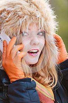 Smiling woman in fur hat talking on mobile phone.