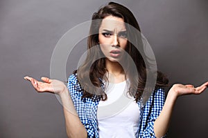 Smiling woman in gesture of asking over gray