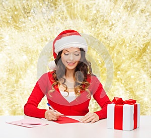 Smiling woman with gift box writing letter
